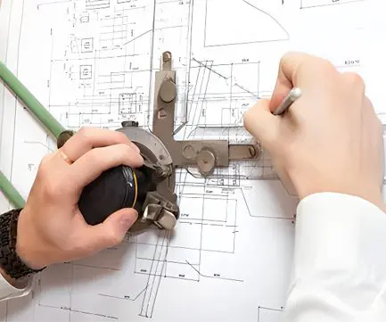 A person working on plans with a pair of scissors.