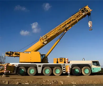 A large crane is on the ground near some dirt.
